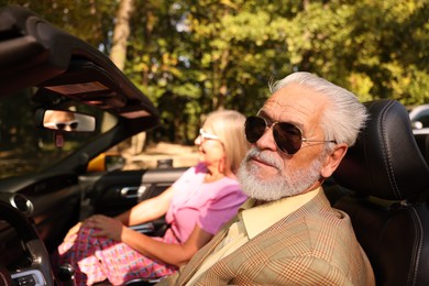 Photo of Senior couple enjoying cabriolet ride in city, selective focus