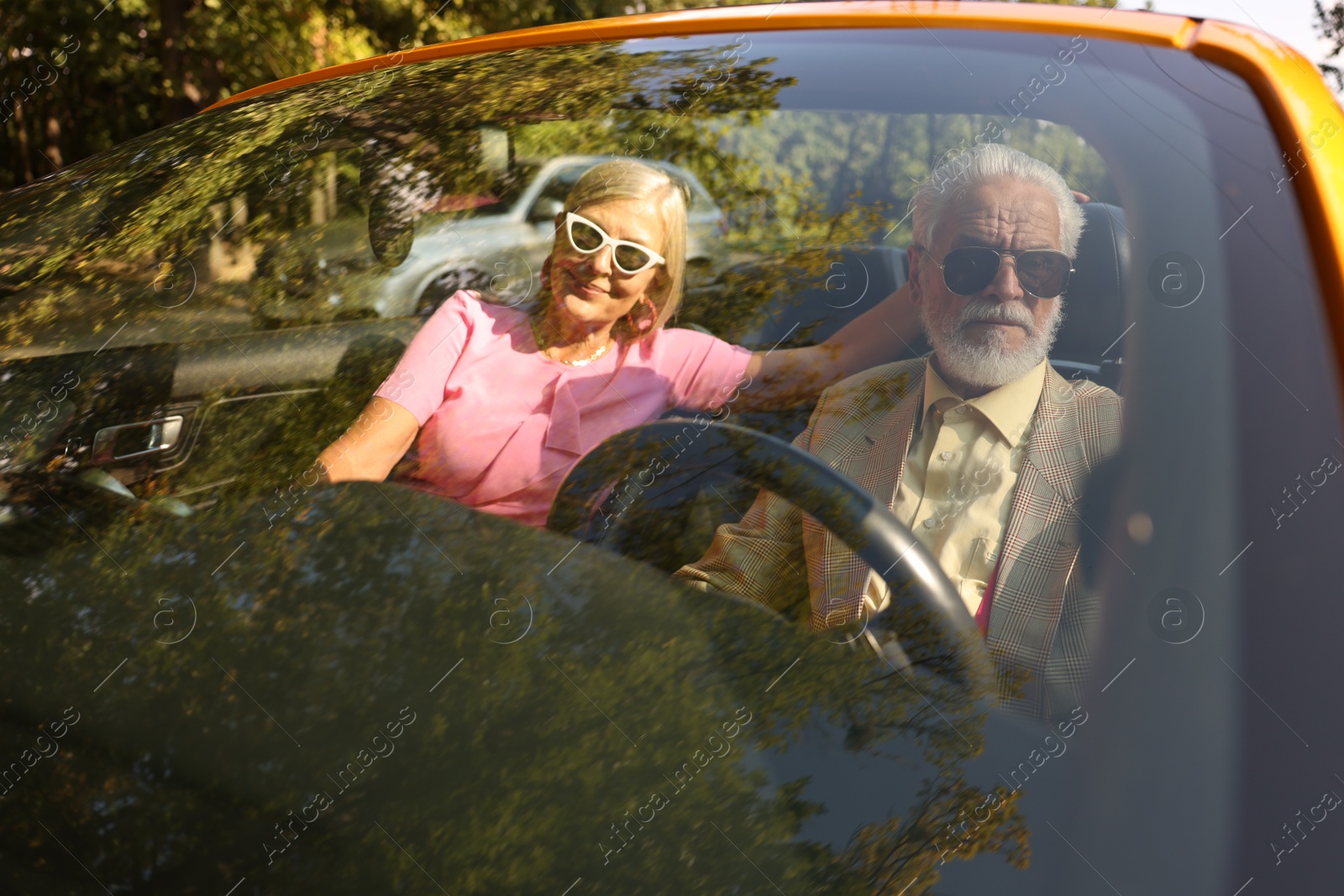 Photo of Senior couple enjoying cabriolet ride in city, view from outdoors