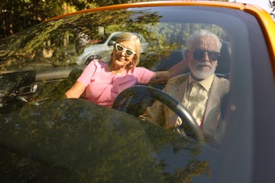 Photo of Senior couple enjoying cabriolet ride in city, view from outdoors