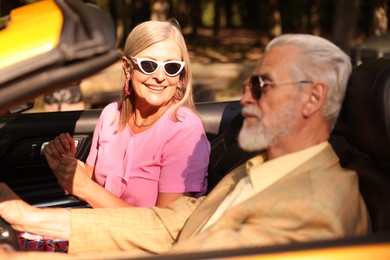 Photo of Senior couple enjoying cabriolet ride in city, selective focus