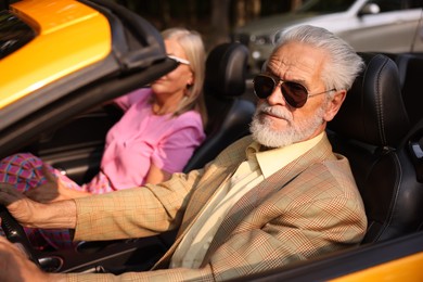 Photo of Senior couple enjoying cabriolet ride in city, selective focus