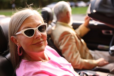 Photo of Senior couple enjoying cabriolet ride in city, selective focus
