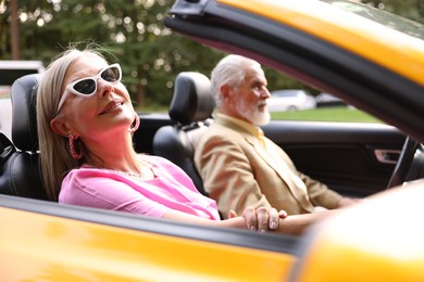 Photo of Senior couple enjoying cabriolet ride in city, selective focus