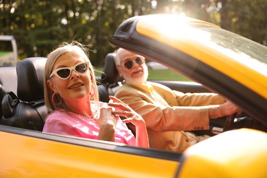 Photo of Senior couple enjoying cabriolet ride in city, selective focus
