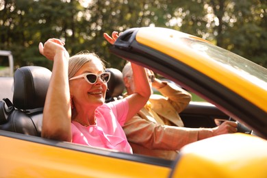 Photo of Senior couple enjoying cabriolet ride in city, selective focus