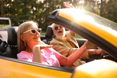 Photo of Senior couple enjoying cabriolet ride in city, selective focus