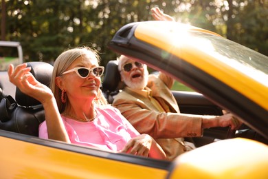 Photo of Senior couple enjoying cabriolet ride in city, selective focus