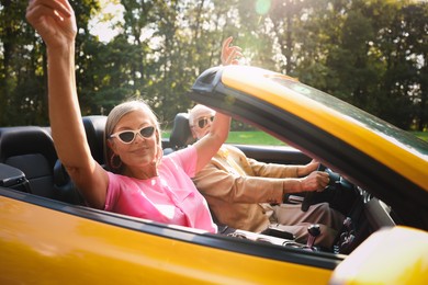 Photo of Senior couple enjoying cabriolet ride in city, selective focus