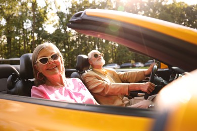 Photo of Senior couple enjoying cabriolet ride in city, selective focus