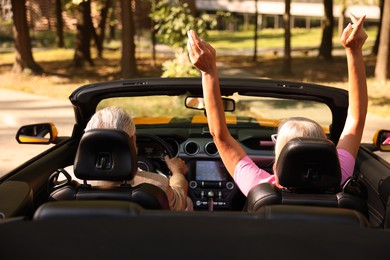 Photo of Senior couple enjoying cabriolet ride in city, back view
