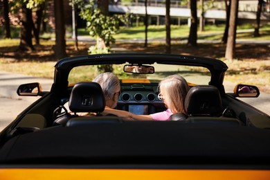 Photo of Senior couple enjoying cabriolet ride in city, back view