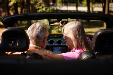Photo of Senior couple enjoying cabriolet ride in city, back view