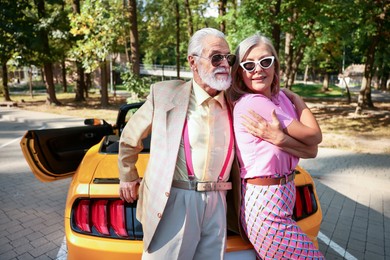Photo of Stylish senior couple in sunglasses near modern cabriolet outdoors