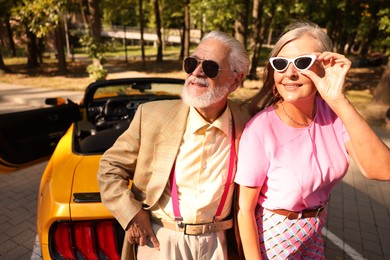 Photo of Stylish senior couple in sunglasses near modern cabriolet outdoors