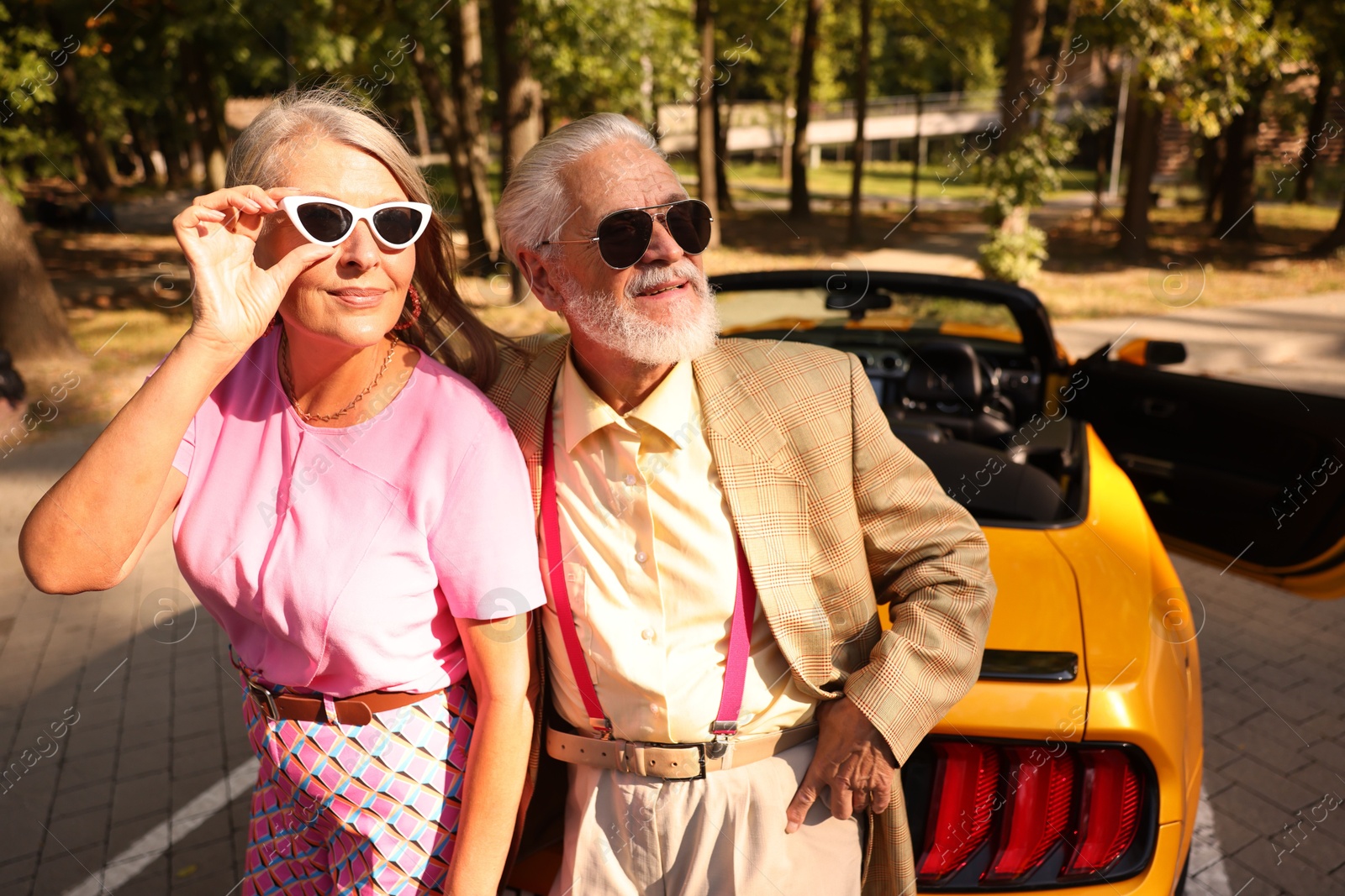 Photo of Stylish senior couple in sunglasses near modern cabriolet outdoors