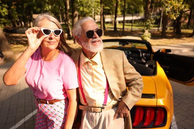 Photo of Stylish senior couple in sunglasses near modern cabriolet outdoors