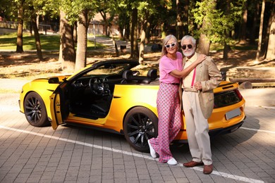 Photo of Stylish senior couple in sunglasses near modern cabriolet outdoors