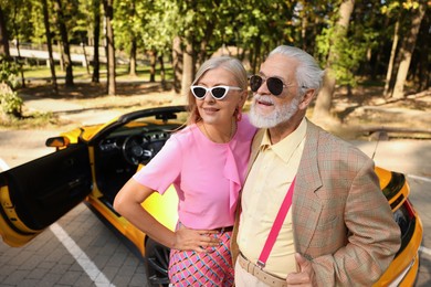 Photo of Stylish senior couple in sunglasses near modern cabriolet outdoors
