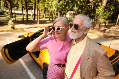Photo of Stylish senior couple in sunglasses near modern cabriolet outdoors