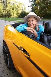 Photo of Stylish senior woman in modern cabriolet outdoors
