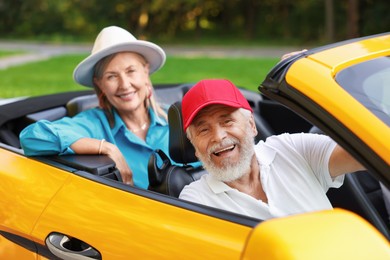 Photo of Senior couple enjoying cabriolet ride outdoors, selective focus
