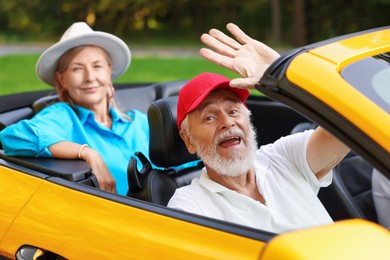 Photo of Senior couple enjoying cabriolet ride outdoors, selective focus