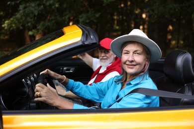 Photo of Senior couple enjoying cabriolet ride outdoors, selective focus