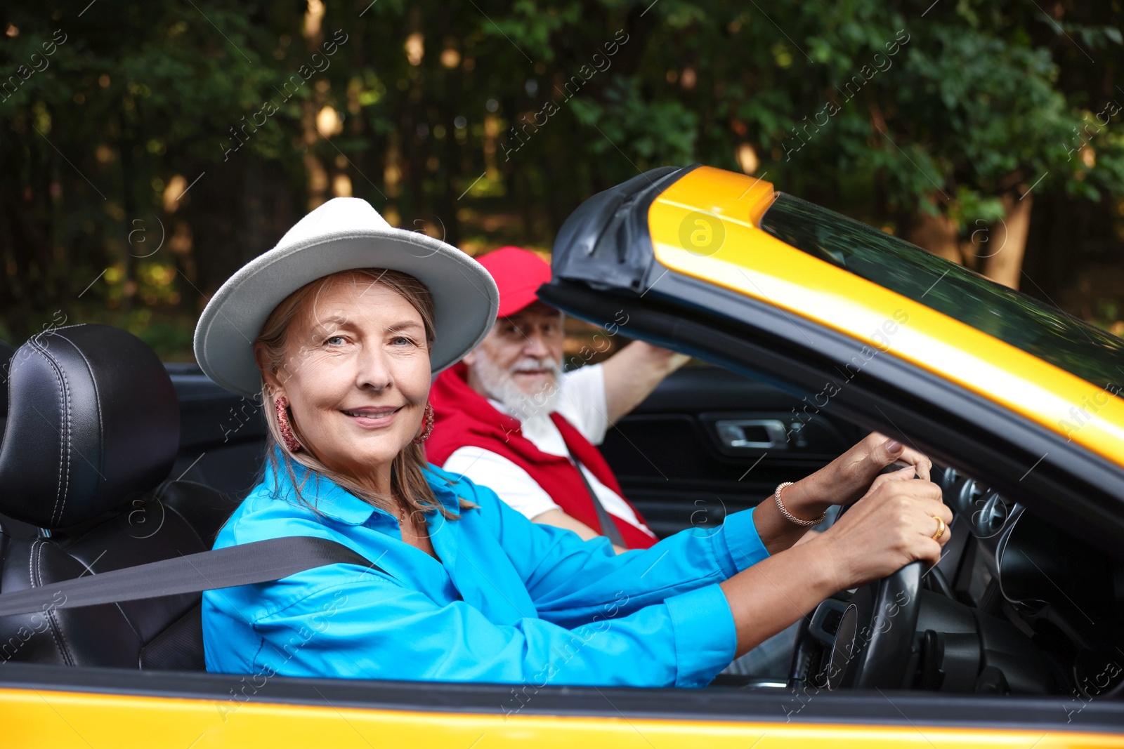 Photo of Senior couple enjoying cabriolet ride outdoors, selective focus