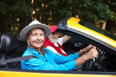 Photo of Senior couple enjoying cabriolet ride outdoors, selective focus