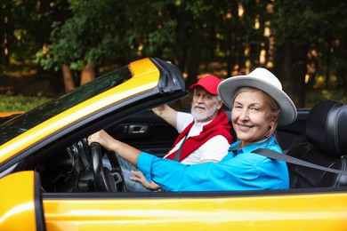 Photo of Senior couple enjoying cabriolet ride outdoors, selective focus