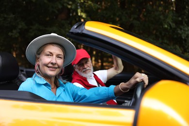 Photo of Senior couple enjoying cabriolet ride outdoors, selective focus