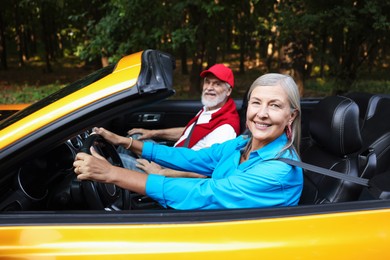 Photo of Senior couple enjoying cabriolet ride outdoors, selective focus