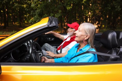 Photo of Senior couple enjoying cabriolet ride outdoors, selective focus