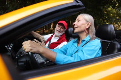 Photo of Senior couple enjoying cabriolet ride outdoors, selective focus