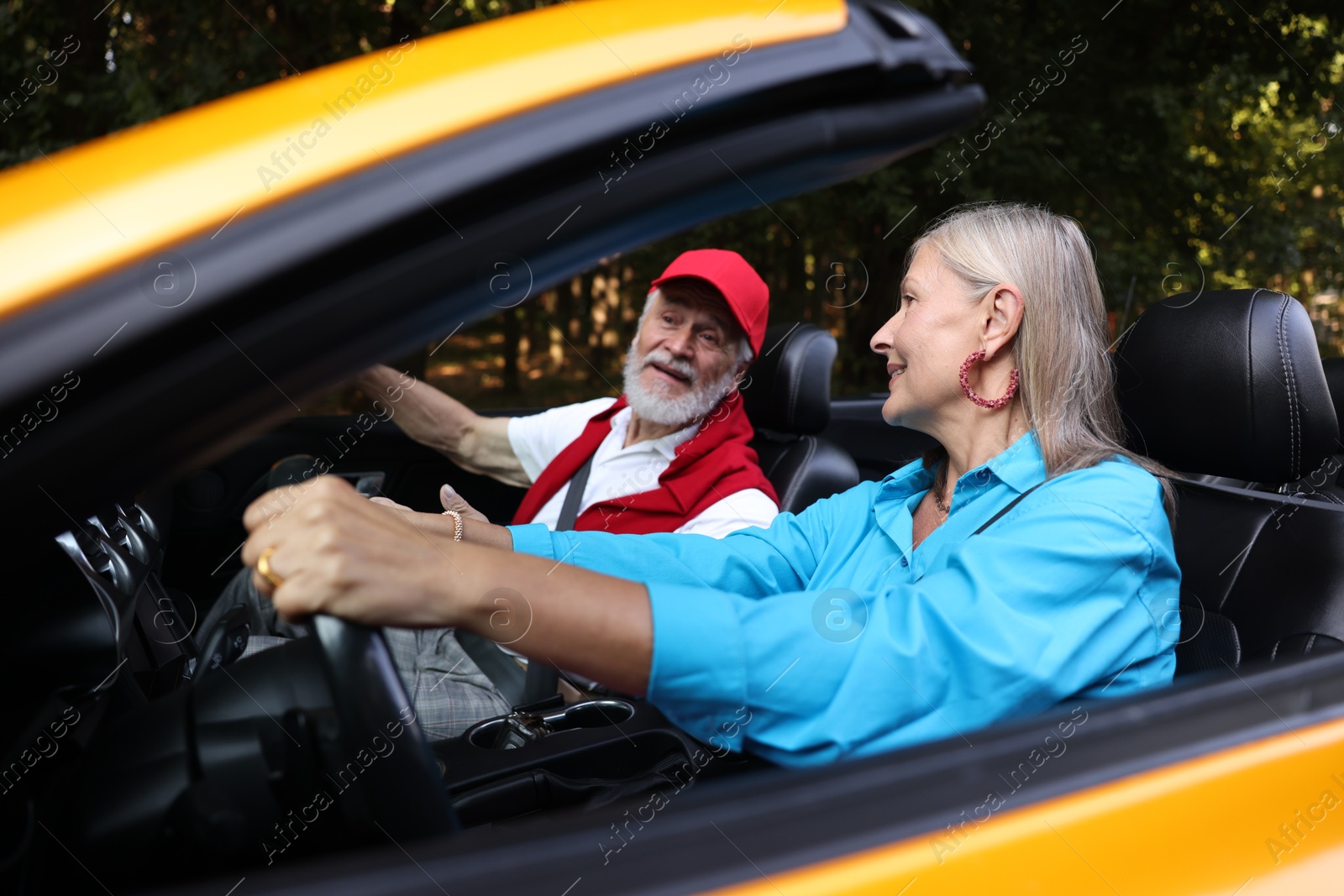 Photo of Senior couple enjoying cabriolet ride outdoors, selective focus