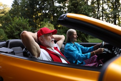 Photo of Senior couple enjoying cabriolet ride outdoors, selective focus
