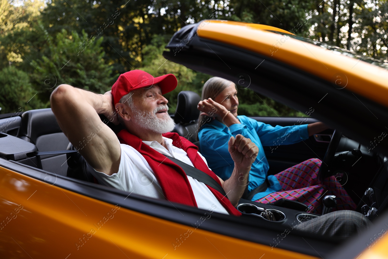 Photo of Senior couple enjoying cabriolet ride outdoors, selective focus
