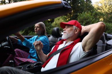 Photo of Senior couple enjoying cabriolet ride outdoors, selective focus