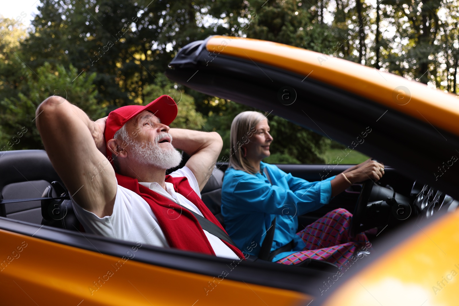 Photo of Senior couple enjoying cabriolet ride outdoors, selective focus