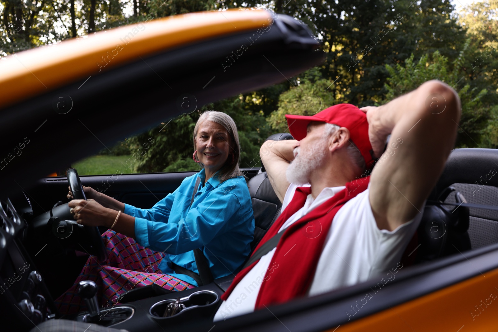 Photo of Senior couple enjoying cabriolet ride outdoors, selective focus