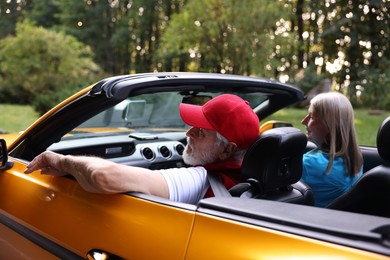 Photo of Stylish senior couple enjoying cabriolet ride outdoors