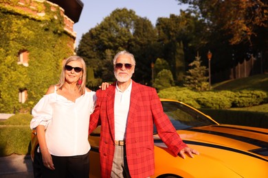 Photo of Stylish senior couple in sunglasses near modern cabriolet outdoors