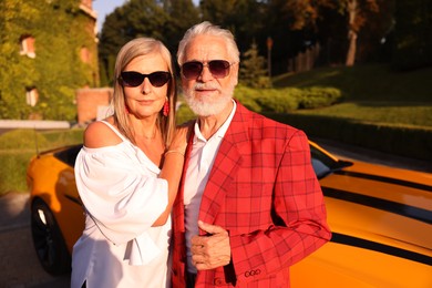 Photo of Stylish senior couple in sunglasses near modern cabriolet outdoors
