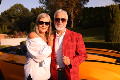 Photo of Stylish senior couple in sunglasses near modern cabriolet outdoors