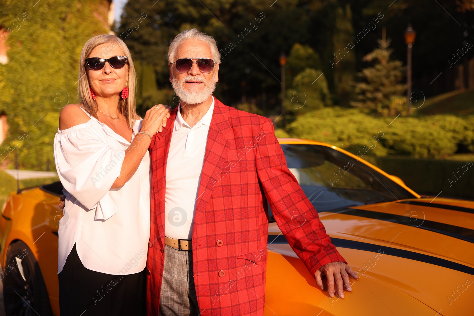 Stylish senior couple in sunglasses near modern cabriolet outdoors Photo of Stylish senior couple in sunglasses near modern cabriolet outdoors