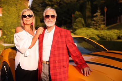 Photo of Stylish senior couple in sunglasses near modern cabriolet outdoors
