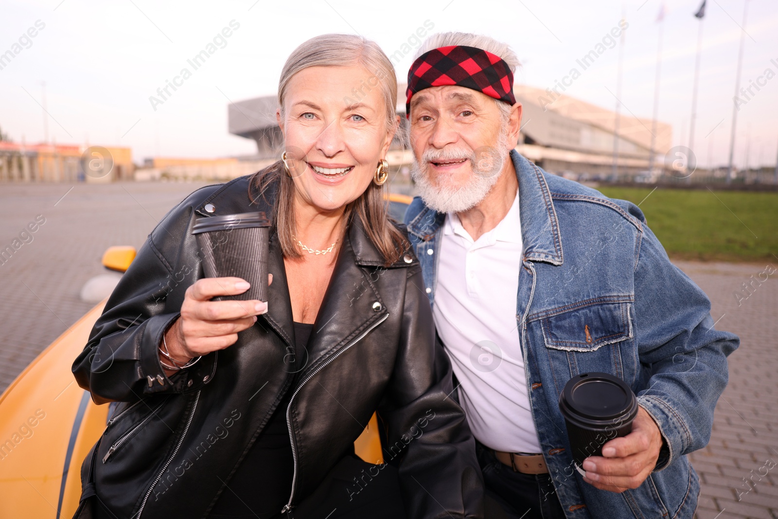 Photo of Stylish senior couple with takeaway coffee near modern cabriolet outdoors