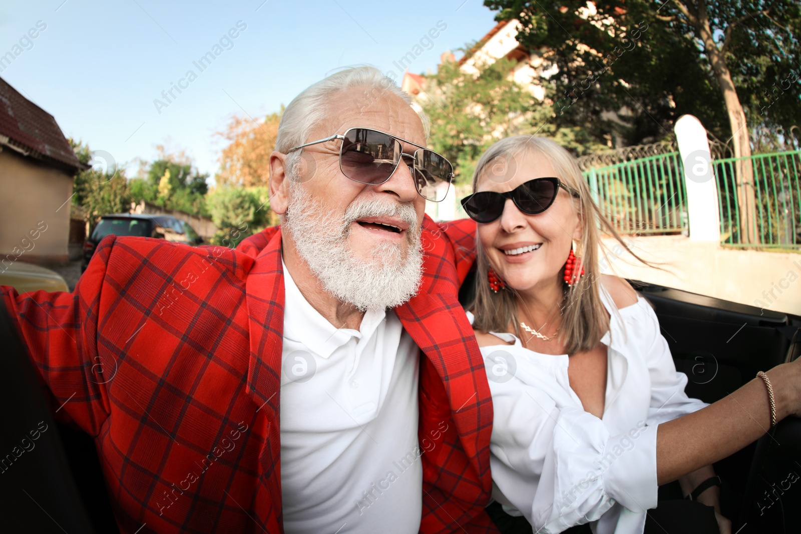 Photo of Senior couple enjoying cabriolet ride in city, wide angle lens