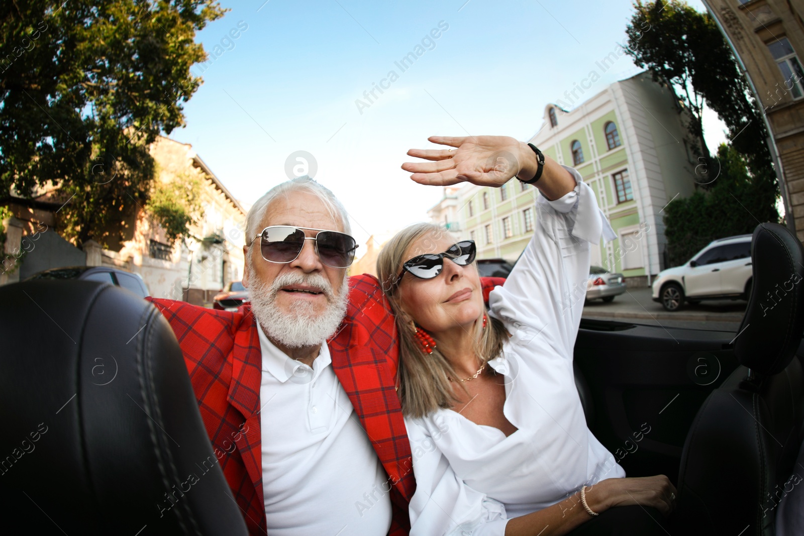 Photo of Senior couple enjoying cabriolet ride in city, wide angle lens