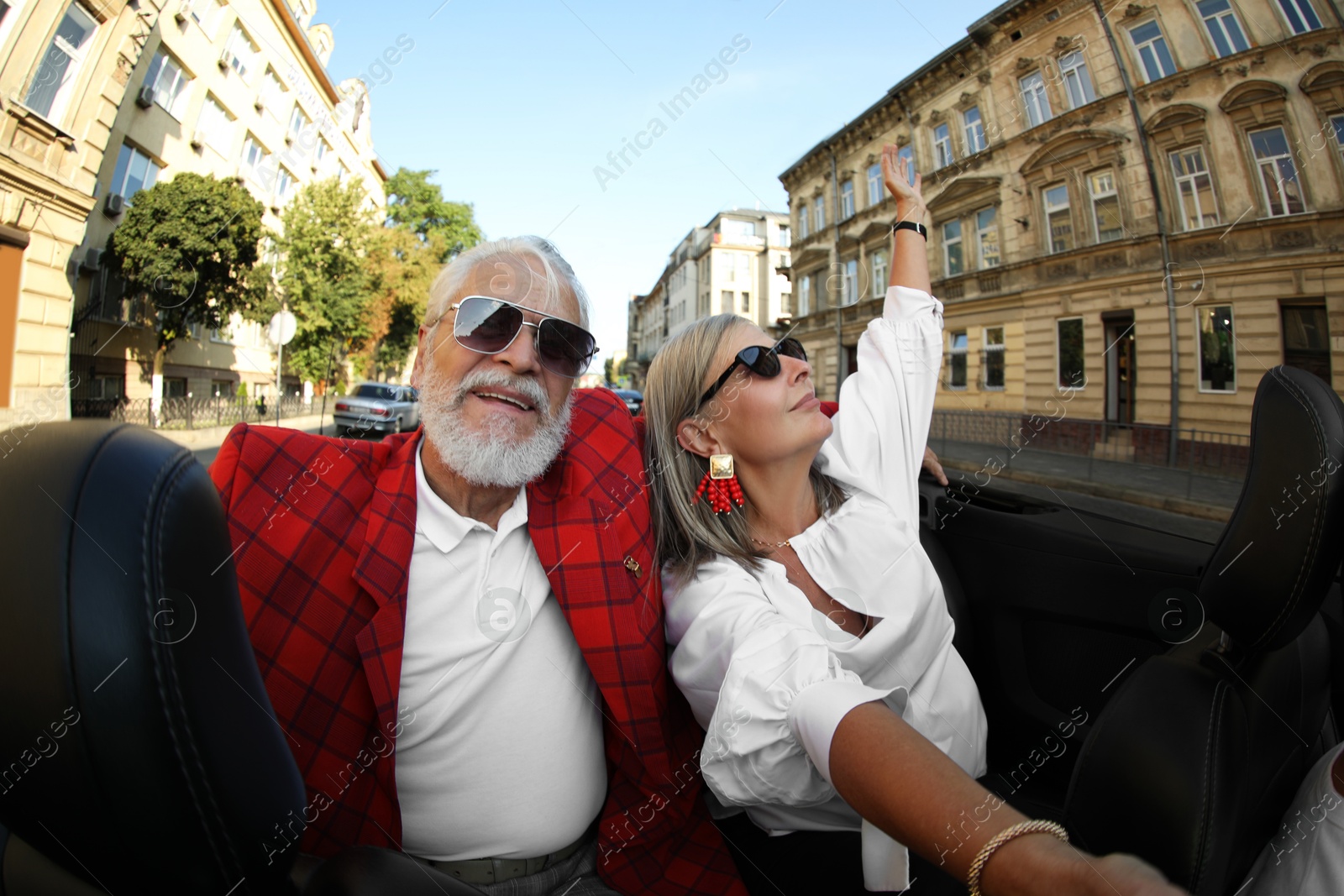Senior couple enjoying cabriolet ride in city, wide angle lens Photo of Senior couple enjoying cabriolet ride in city, wide angle lens